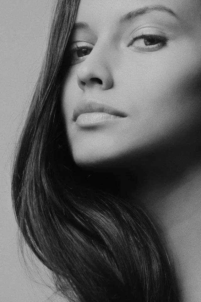 Black and white close-up of a woman's face with smooth skin and flowing hair.