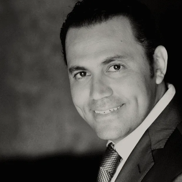 Young man in a suit smiling confidently, representing professionalism and trust for a plastic surgery center.