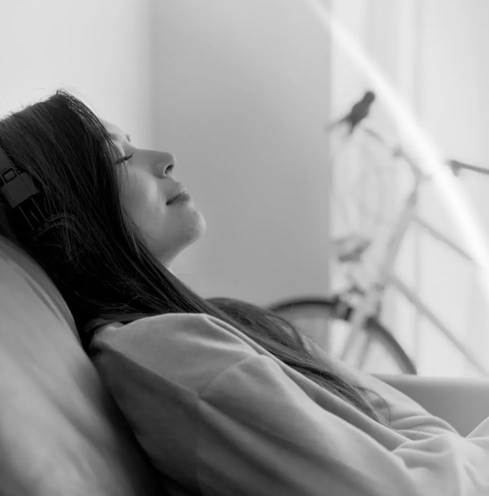 Person relaxing with headphones on, highlighting tranquility and comfort at a plastic surgery center.