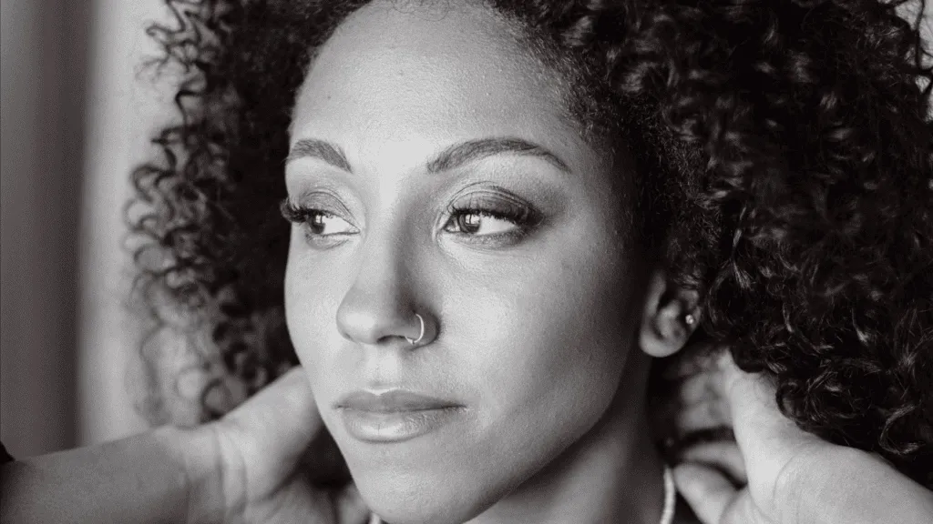 Black and white close-up photo of a woman with curly hair and a nose ring, looking off to the side.