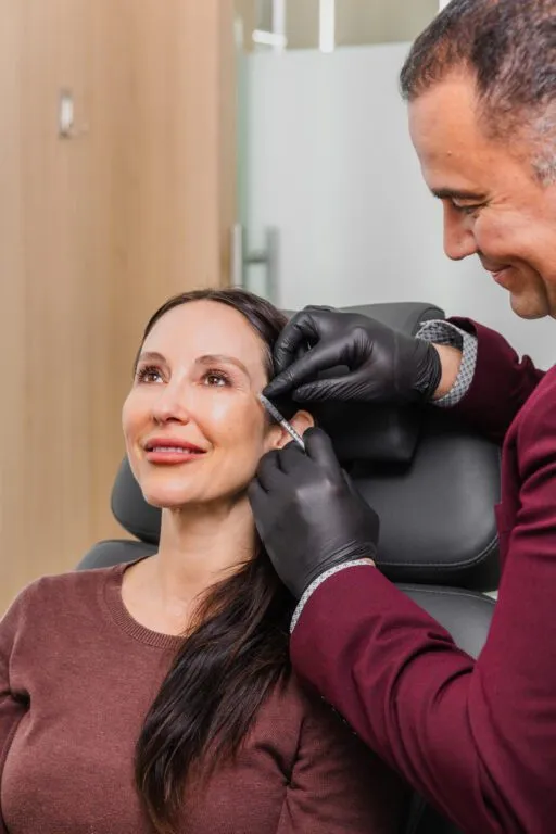Doctor performing cosmetic injection on woman at plastic surgery center.