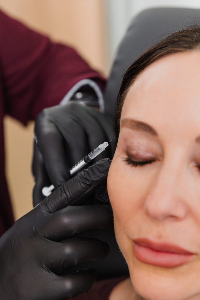 Patient receiving cosmetic injection in the cheek at a plastic surgery center.