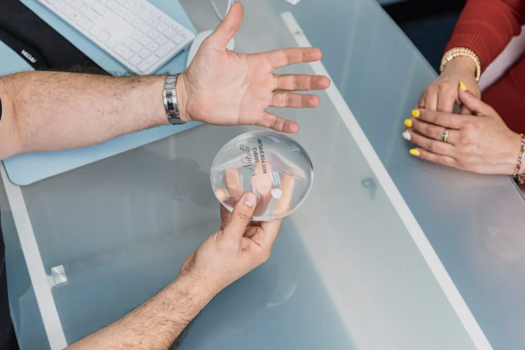 Doctor discussing breast implant options with a patient at a plastic surgery center.