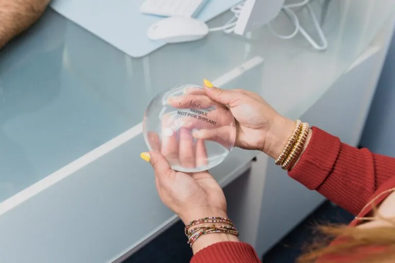 Hands holding a sample breast implant at a plastic surgery center.