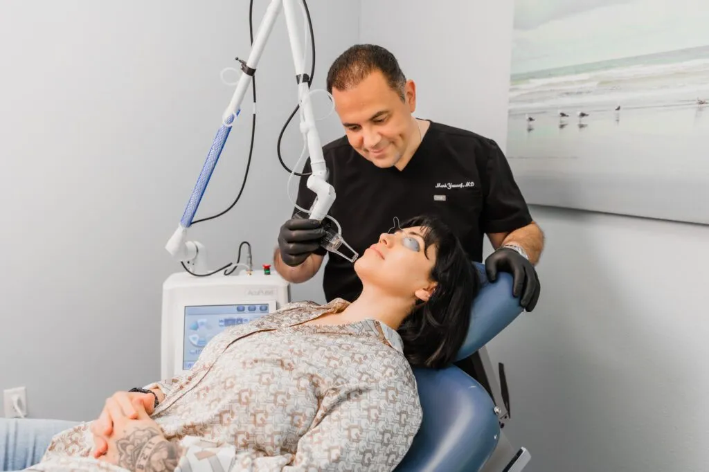 Doctor performing a laser treatment on a patient at a plastic surgery center.