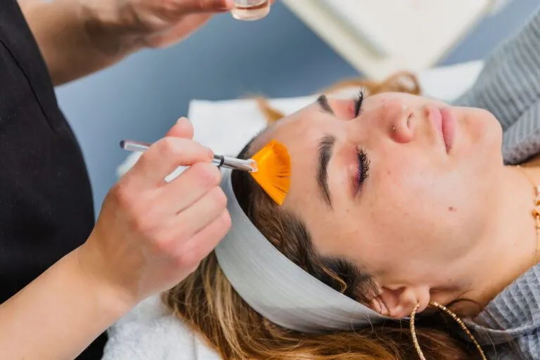 Patient receiving facial treatment with a brush at a plastic surgery center.