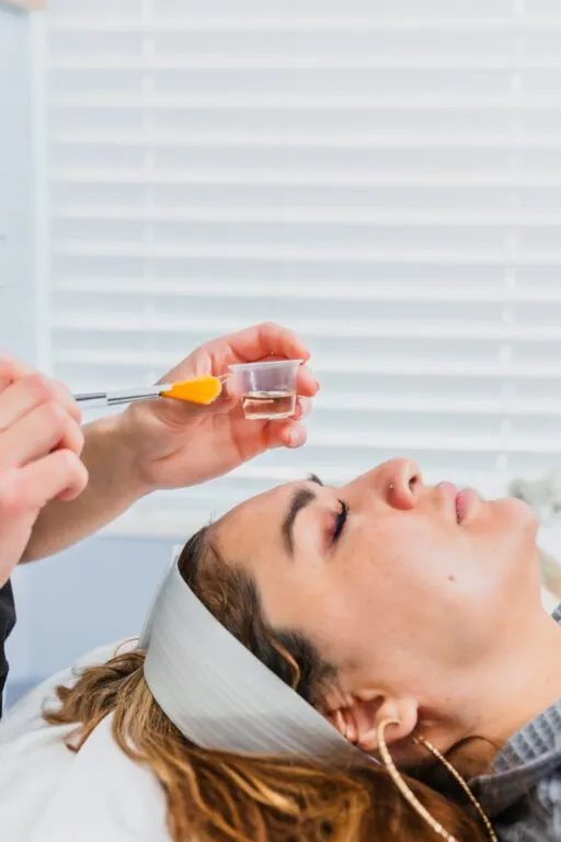 Person receiving a skincare treatment with a brush and liquid.