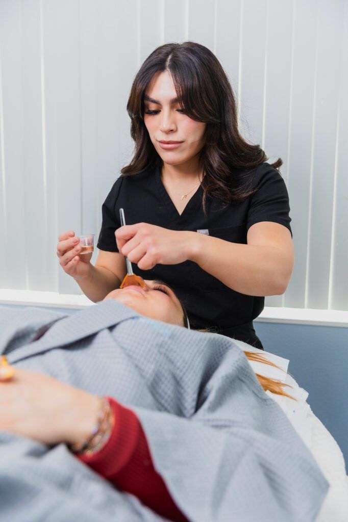 Aesthetician performing facial treatment procedure at a plastic surgery center.