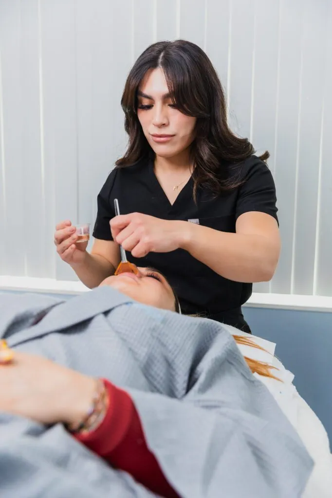 Aesthetician performing facial treatment procedure at a plastic surgery center.