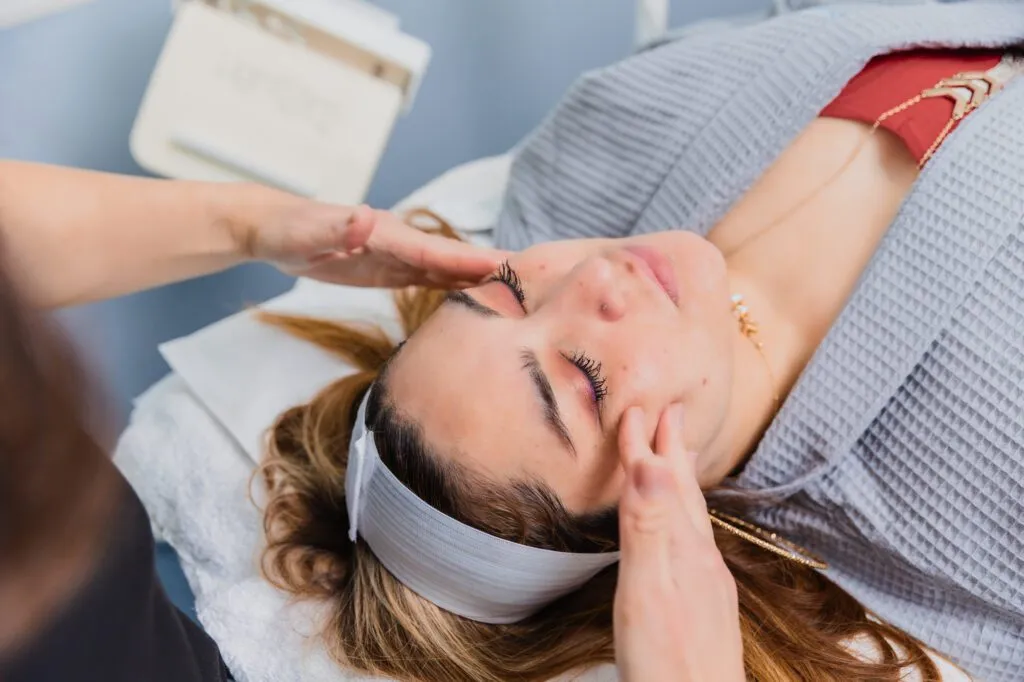 Woman receiving facial massage treatment at a plastic surgery center.