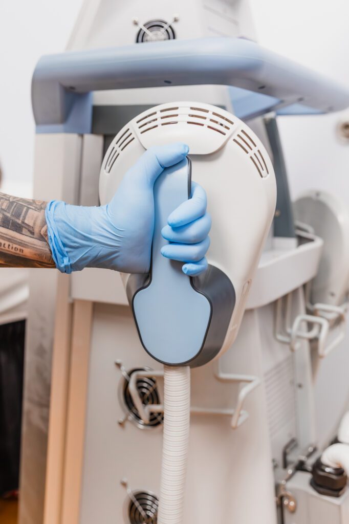Gloved hand holding laser lipo machine handle at plastic surgery center.