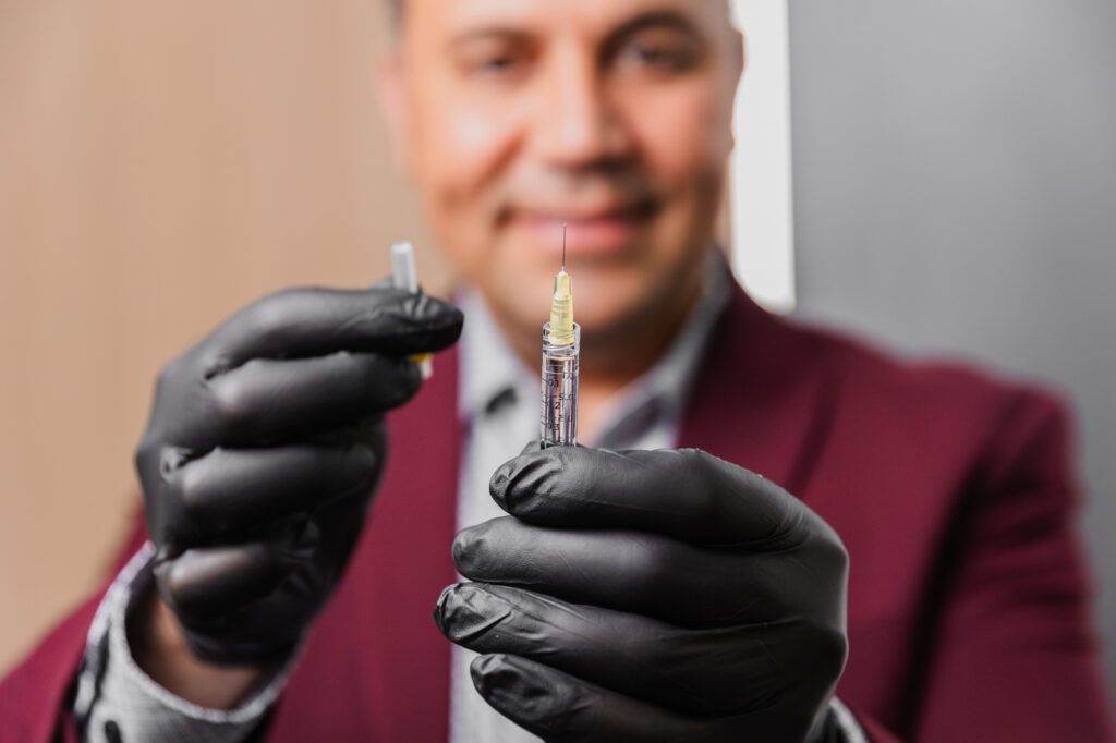 Gloved hands holding a syringe for cosmetic injections at a plastic surgery center.