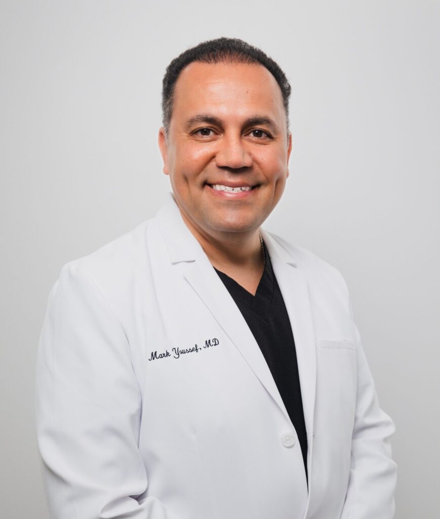 Smiling plastic surgeon in a white coat at a medical center.