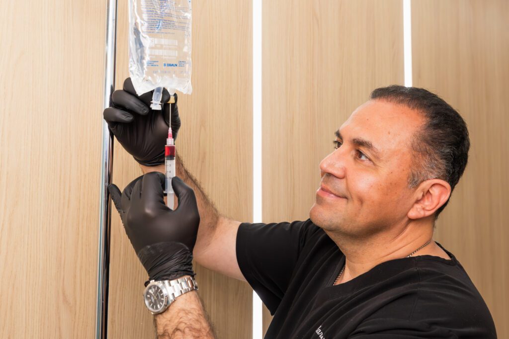 Smiling doctor preparing an IV drip at a plastic surgery center.