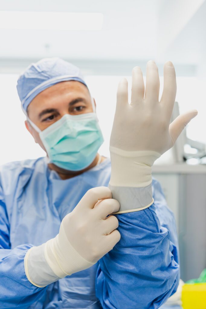 Plastic surgeon preparing for surgery by putting on sterile gloves.