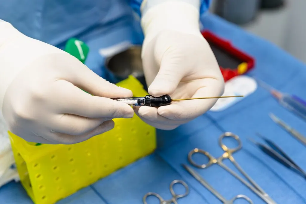 Gloved hands holding a surgical instrument in a plastic surgery operating room.