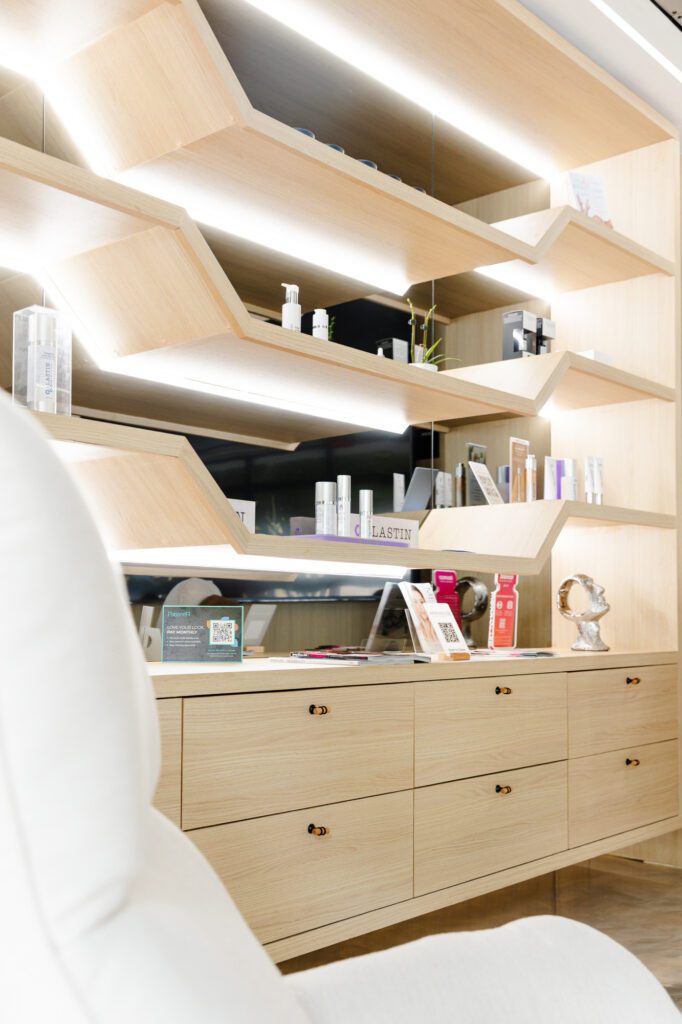 Modern plastic surgery center interior with wooden shelves displaying skincare products.
