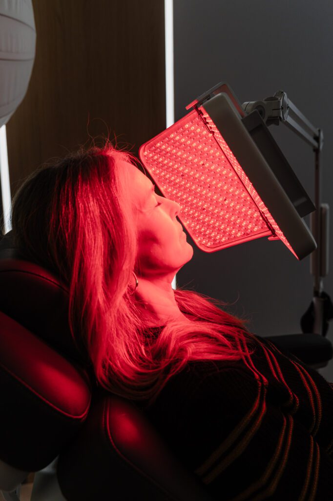 Woman receiving LED light therapy treatment at plastic surgery center.