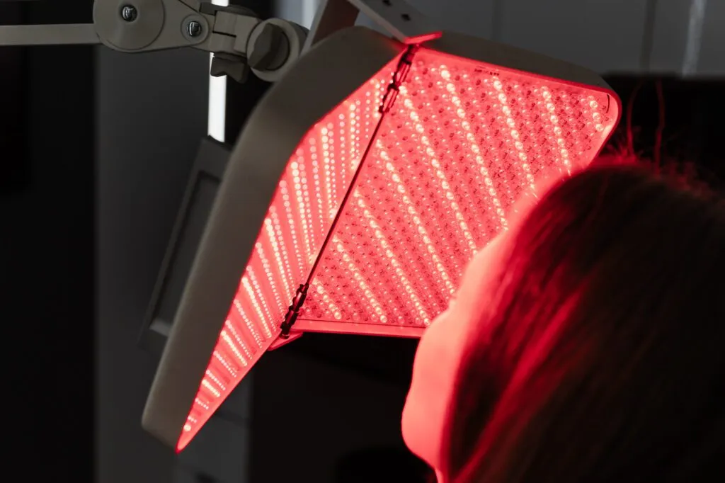 Person receiving LED light therapy treatment at a plastic surgery center.