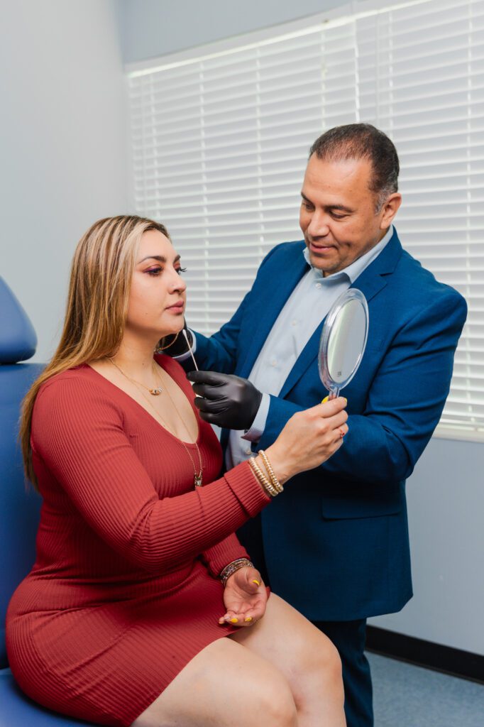 Plastic surgeon consulting with a patient holding a mirror in a clinic setting.