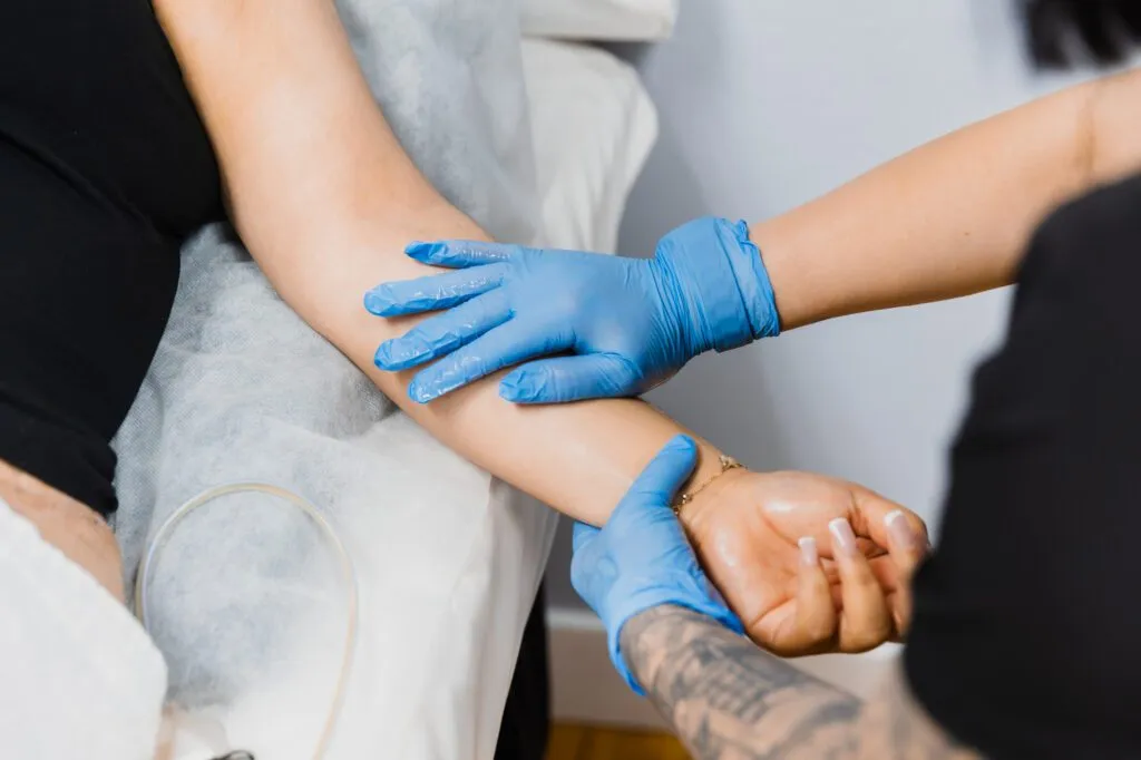 Healthcare professional wearing blue gloves preparing a patient for an IV procedure.