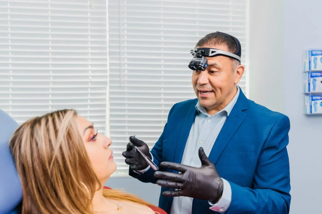 A medical professional wearing a headlamp examines a woman lying on a clinic bed.
