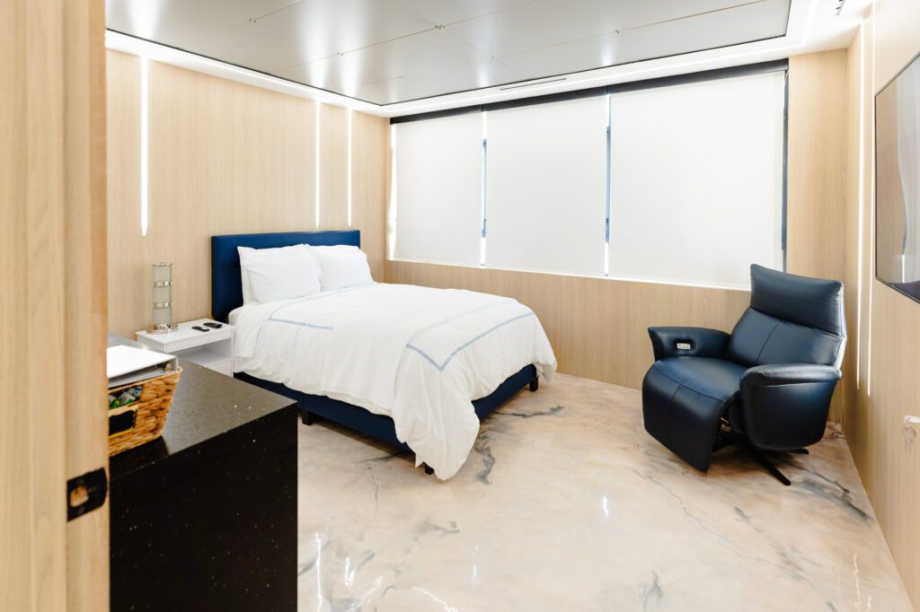 Modern recovery room with comfortable bed and recliner at a plastic surgery center.