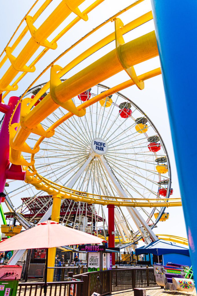 Bright and colorful amusement park with Ferris wheel and roller coaster under a clear sky.