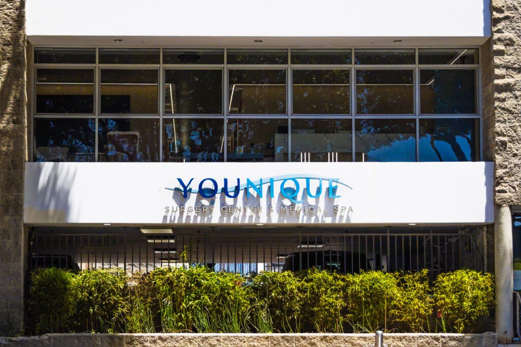 Exterior of a plastic surgery center with signage reading "Younique Surgery Center & Medical Spa".