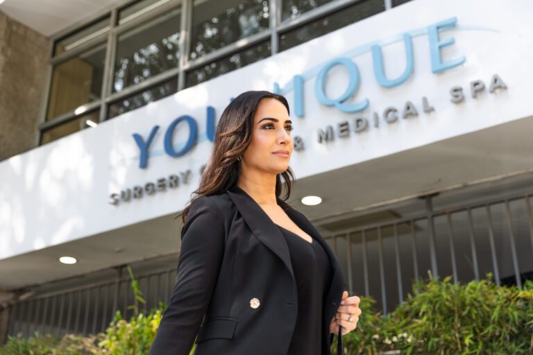 Woman standing confidently in front of a plastic surgery center building.