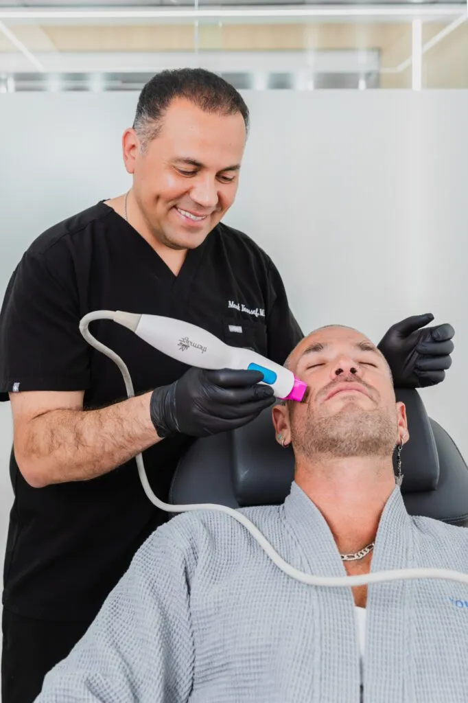 Dermatologist performing a laser skin treatment on a male patient in a clinic setting.