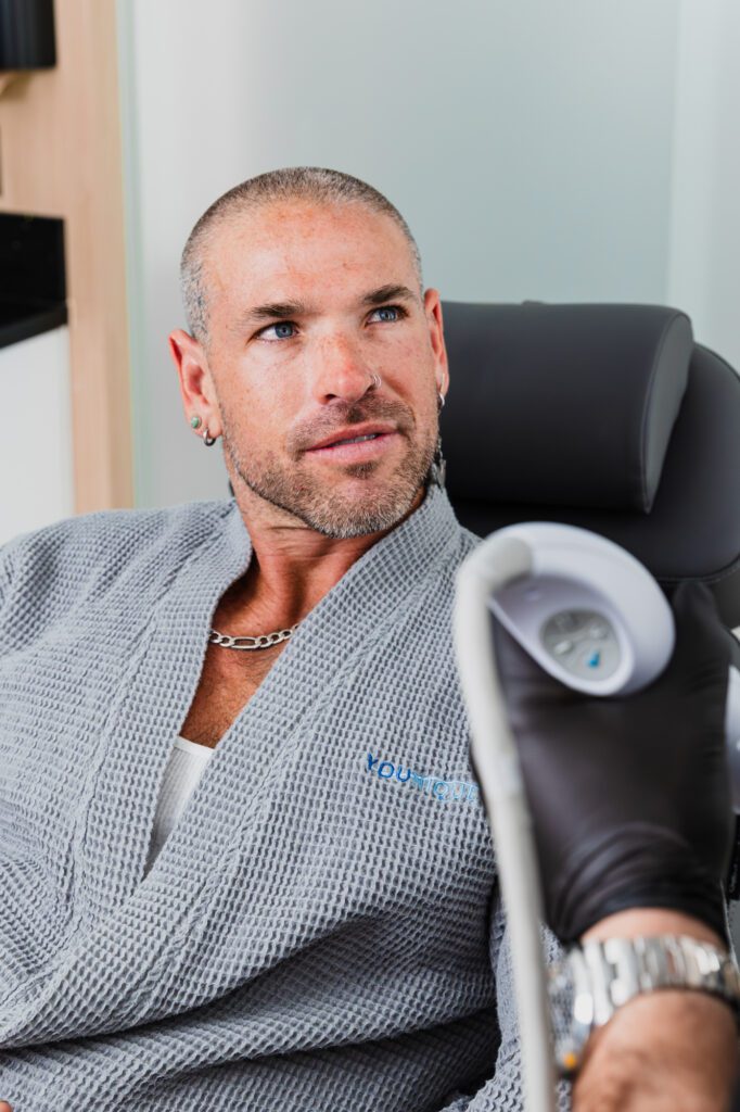 Man receiving a cosmetic treatment in a clinic, wearing a gray robe.