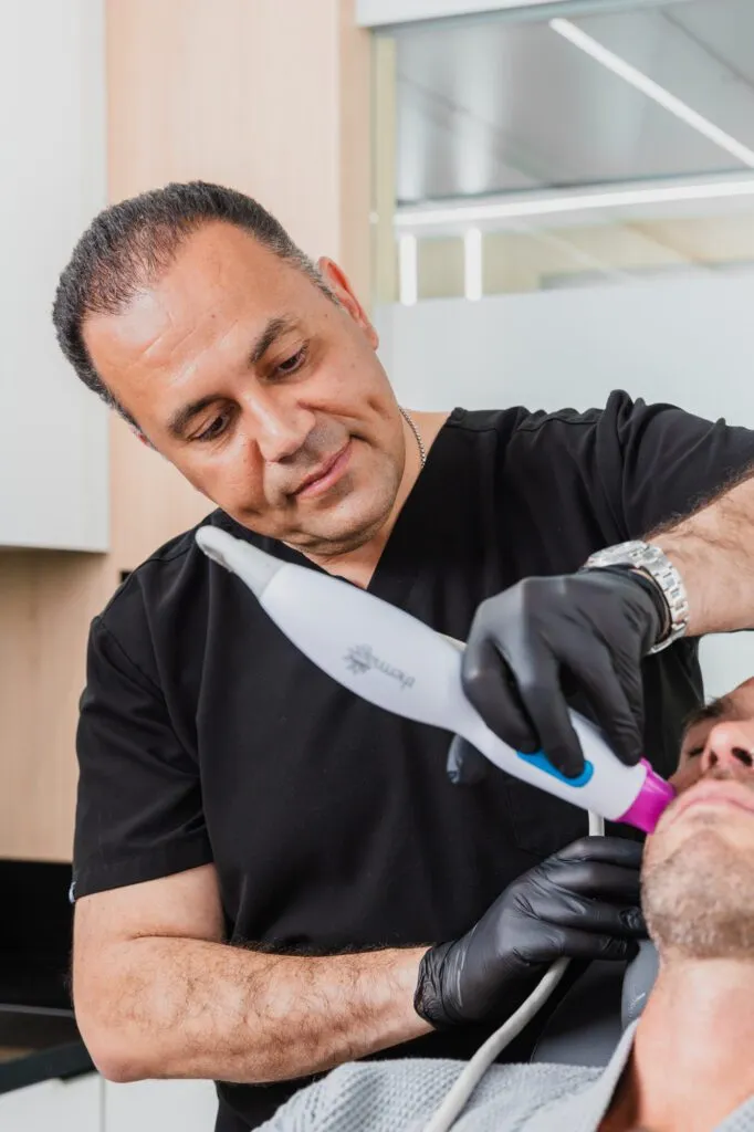Plastic surgeon performing a facial treatment with advanced equipment.