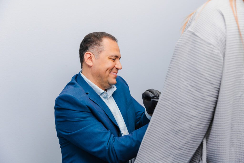 Plastic surgeon consulting with a patient wearing a striped shirt.