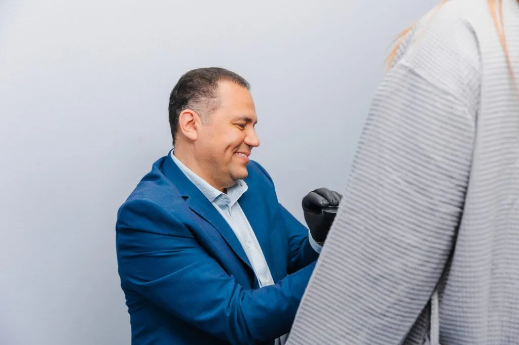 Plastic surgeon consulting with a patient wearing a striped shirt.