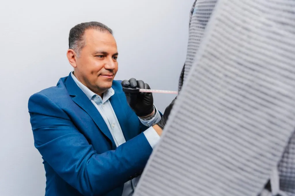 Plastic surgeon in blue suit measuring with tape during consultation.
