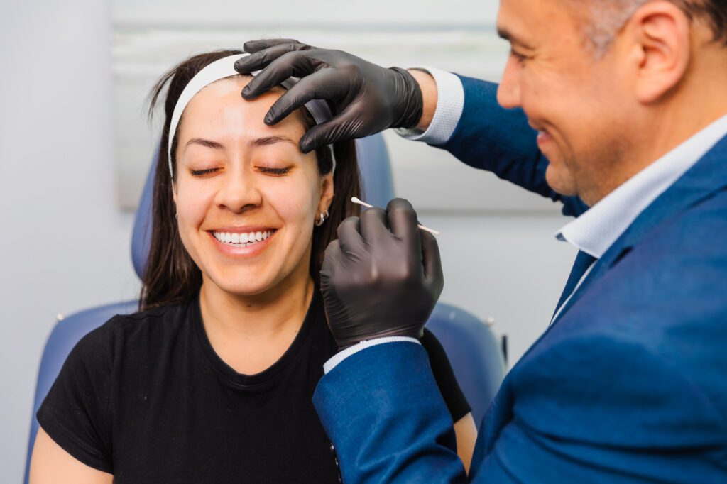 Patient smiling while receiving a skincare treatment at a plastic surgery center.