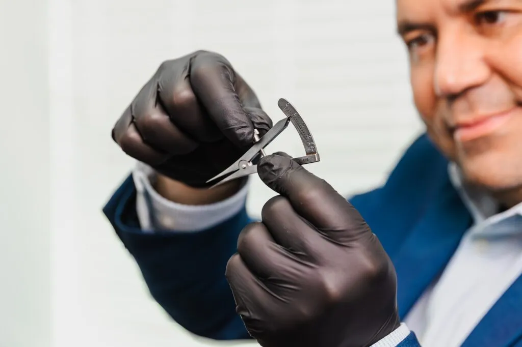 Plastic surgeon with caliper and gloves for precise measurements.